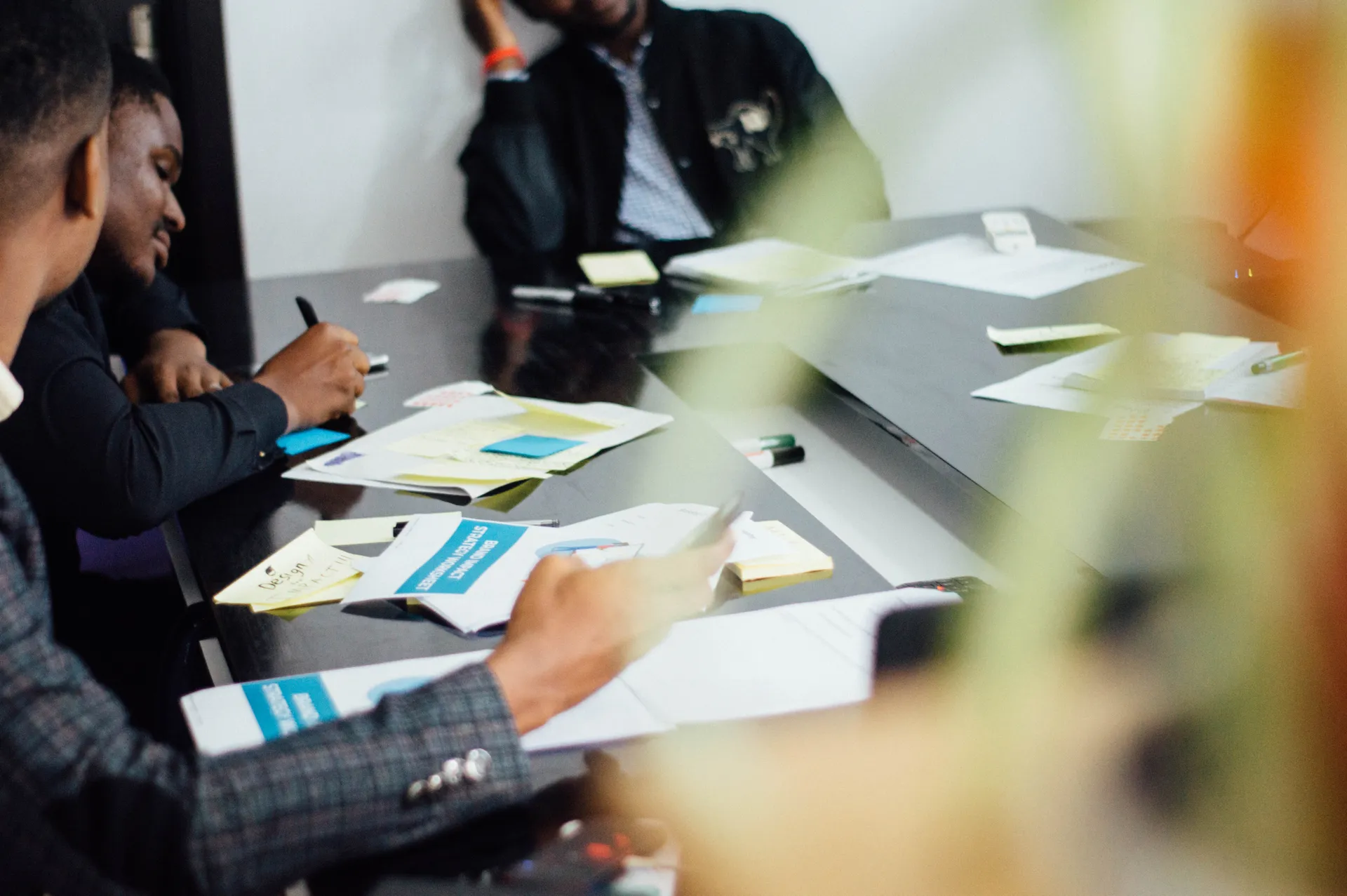 People working through ideas together around a table with notebooks and sticky notes.